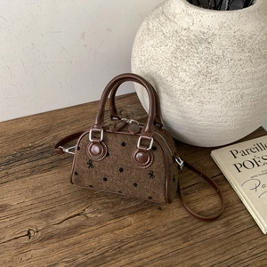Brown barrel crossbody bag with polka dots and bow embroidery in a minimalist setup