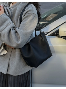 Close-up of black litchi grain leather bucket bag showing texture and slim shoulder strap