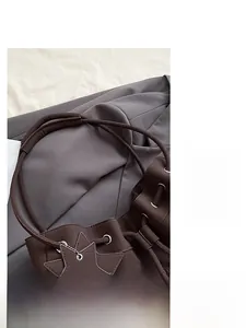 Detail of dark brown pebble leather bucket bag with drawstring eyelets and star charm