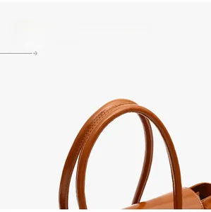 Macro view of caramel leather handbag handle with detailed double-stitched craftsmanship