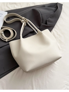 Detailed macro of minimalist beige bucket bag featuring high-quality lychee grain leather