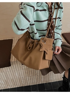 Detail of brown leather tote bag with star charm, luggage tag and drawstring closure
