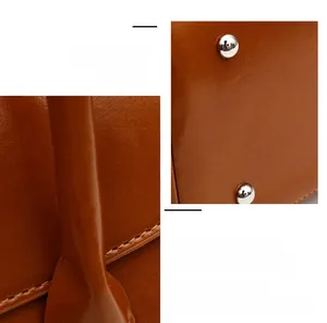 Detail of fine stitching and silver spherical metal rivets on brown leather tote bag