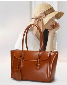 Detail view of brown glossy leather tote bag with dual shoulder straps and hangtag