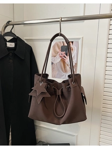 Detail of brown faux leather tote bag with star charms and drawstring design