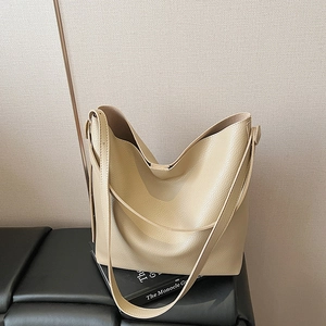 Grande borsa hobo in pelle martellata beige da donna su una panca in pelle vintage