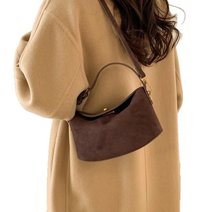 Deep brown suede half-moon crossbody bag with gold hardware shown on a model