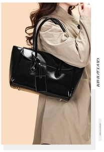 Detail of glossy black leather tote bag featuring bottom metal studs and a matching hangtag