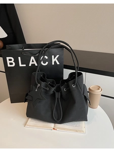 Detail of black drawstring bucket bag with star pendant on a white table setting