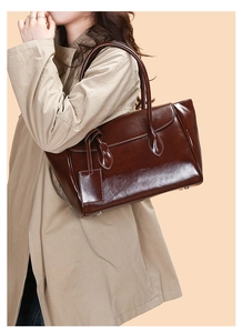 Model wearing dark brown glossy leather tote bag with elegant vintage shoulder style