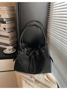 Minimalist black leather bucket bag with star charm and textured lychee pattern