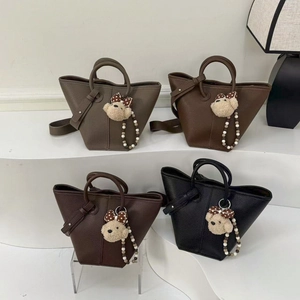 Minimalist leather bucket bags in four earth tones with cute bear charms on a clean display