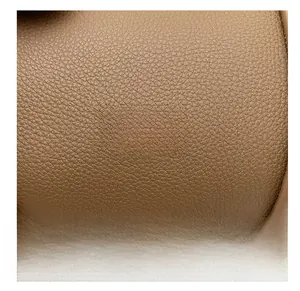 Macro shot of brown lychee grain leather texture with gold rivet brand tag details