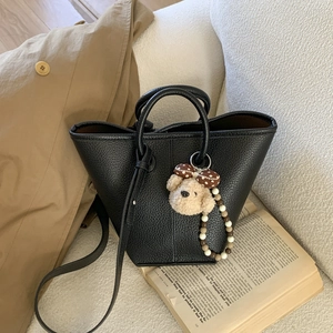 Classic black litchi pattern leather bucket bag with a cute plush bear charm accessory