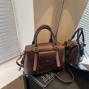 Sac Boston rétro marron foncé avec doubles poignées et détails dorés sur un miroir