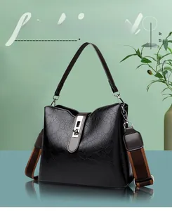 Close-up of black textured bucket bag with silver clasp lock and wide fabric strap