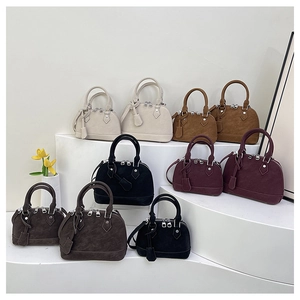 Gros plan de sacs à main en forme de coquille aux tons beige, marron et bordeaux