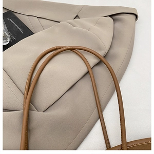Detail view of brown leather tote bag cylindrical handle with reinforced stitching