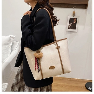 Detailed macro view of the cream tote bag leather texture with brown trim and fashion tag