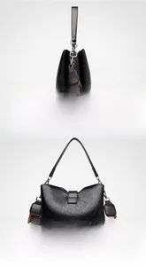 Detail view of black bucket bag with cracked texture and brown fabric shoulder strap