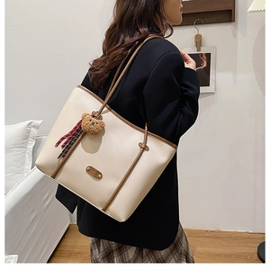 Detail of off-white tote bag with lychee texture, brown strap and cute bear pendant