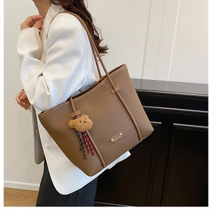 Detailed texture of brown lychee leather tote bag with vertical straps and bear charm