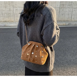 Detail view of dark brown suede crossbody bag with silver studs on a fashion model