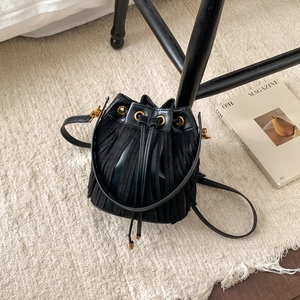 Retro black leather bucket bag with tassels, drawstring closure and gold hardware accents