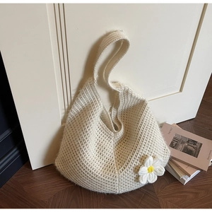 Detail of a beige knit hobo bag with a woven flower charm and mesh texture design
