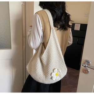 Close-up of cream knit shoulder bag featuring a 3D daisy flower detail on a model