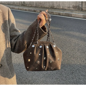 Detail of dark brown suede cloud bag featuring silver studs and adjustable chain strap