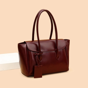 Deep red leather tote bag with long shoulder straps shown on a minimalist background