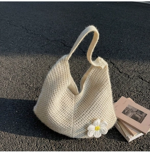 Close-up of beige knit hobo bag with textured crochet pattern and daisy flower detail
