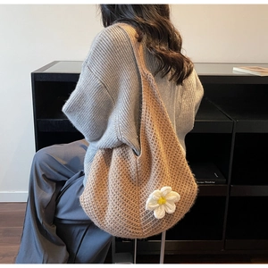 Detail view of brown crochet tote bag with 3D white flower and thick woven texture