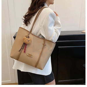 Macro shot of large khaki tote bag with lychee grain texture and cute bear charm