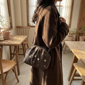 Detail of dark brown suede crossbody bag with silver rivets and metal chain strap