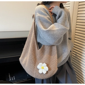 Close-up of brown knit crochet tote bag featuring white daisy floral detail and weave texture