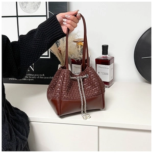 Detail of dark brown bucket bag featuring woven leather pattern and pearl chain drawstring