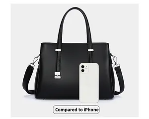 Front view of black leather tote bag next to a white iPhone for size comparison