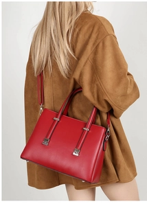 Detail of red textured leather tote bag featuring silver hardware and crossbody strap