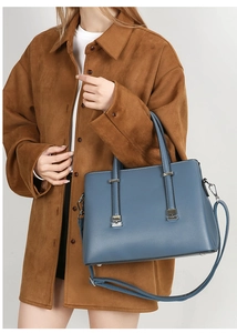 Close-up of a blue leather tote bag featuring a silver buckle and detachable shoulder strap