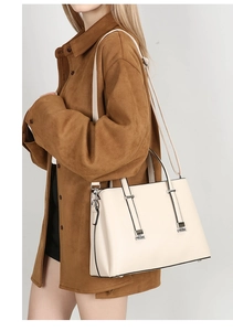 Detail of cream leather tote bag with silver hardware on brown suede jacket outfit