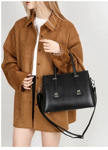 Detail of black leather tote bag with silver accents and adjustable shoulder strap