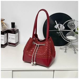 Detail of red faux leather bucket bag with woven upper and pearl chain drawstring