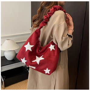 Detail of red suede tote bag with white star embroidery and ruched shoulder strap