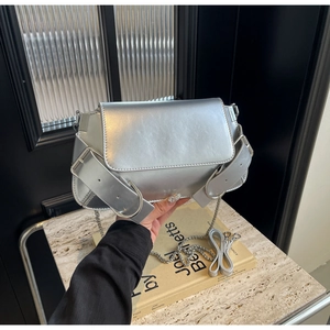 Silver metallic crossbody bag with dual straps and decorative buckles in y2k style