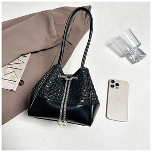 Close-up of black woven leather bucket bag with silver chain and pearl drawstring