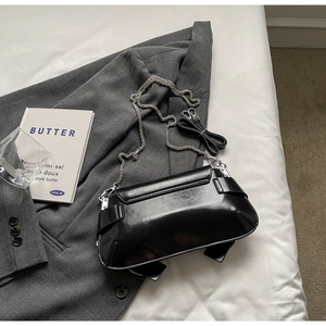 Detail of minimalist black leather crossbody bag with silver metal chain and shoulder strap