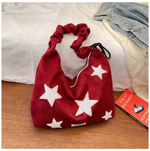 Detail of red faux suede tote bag with white star print and trendy ruched shoulder strap