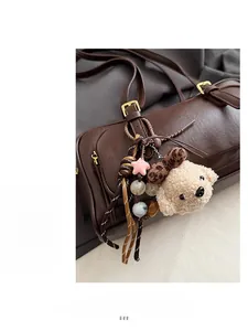 Detail view of a beige teddy dog plush charm with star accessories on a brown leather bag